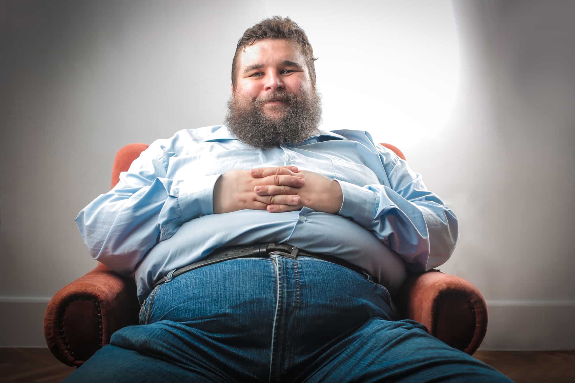 Массивный толстый молодой человек со стриженою. Толстый человек сидит. Толстяк сидит. Живот Толстого человека сидящего.